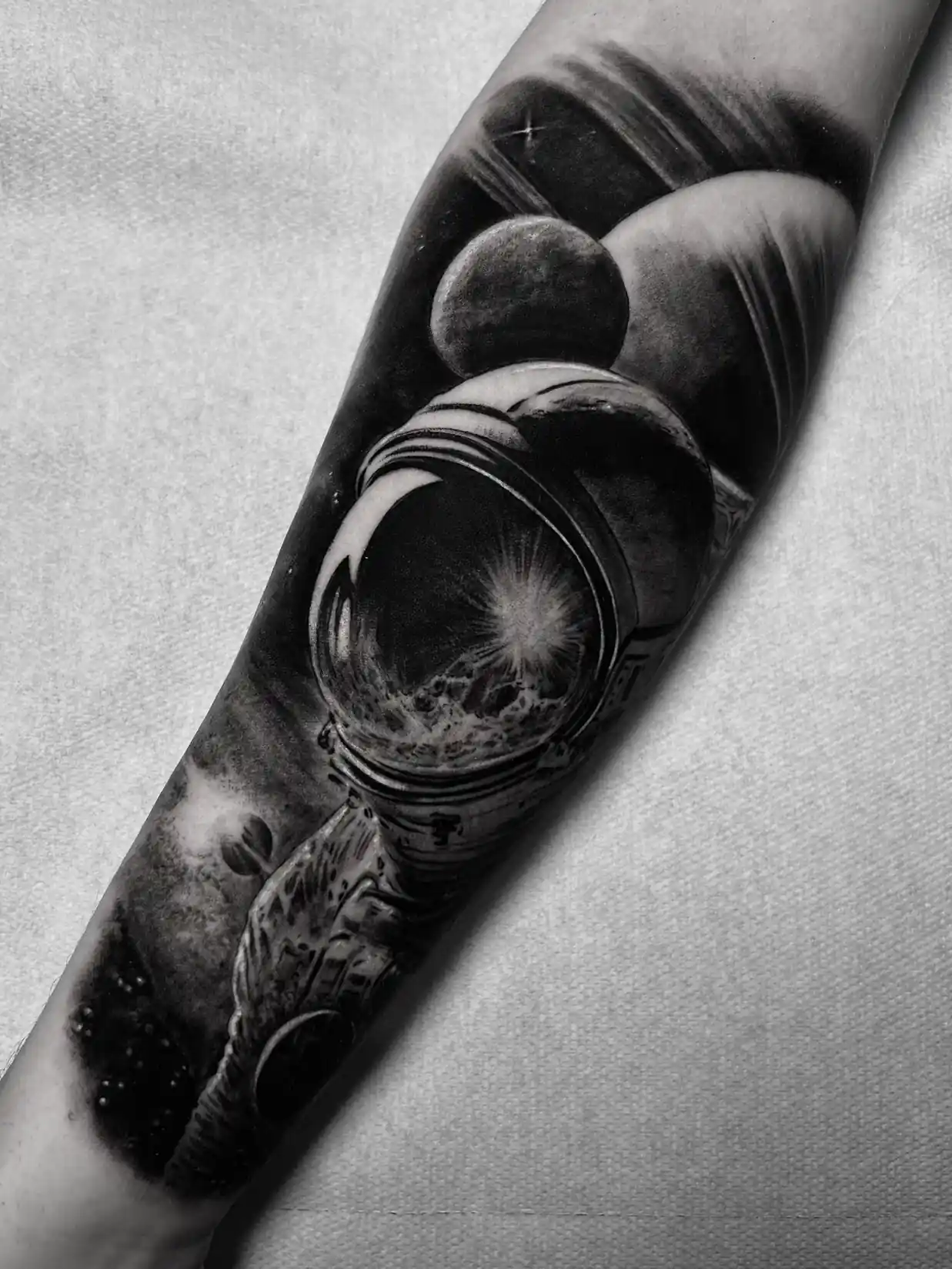 Tatouage réaliste noir et gris d'un astronaute sur l'avant-bras — Jeremy Lorenzato, Art du Noir Nice