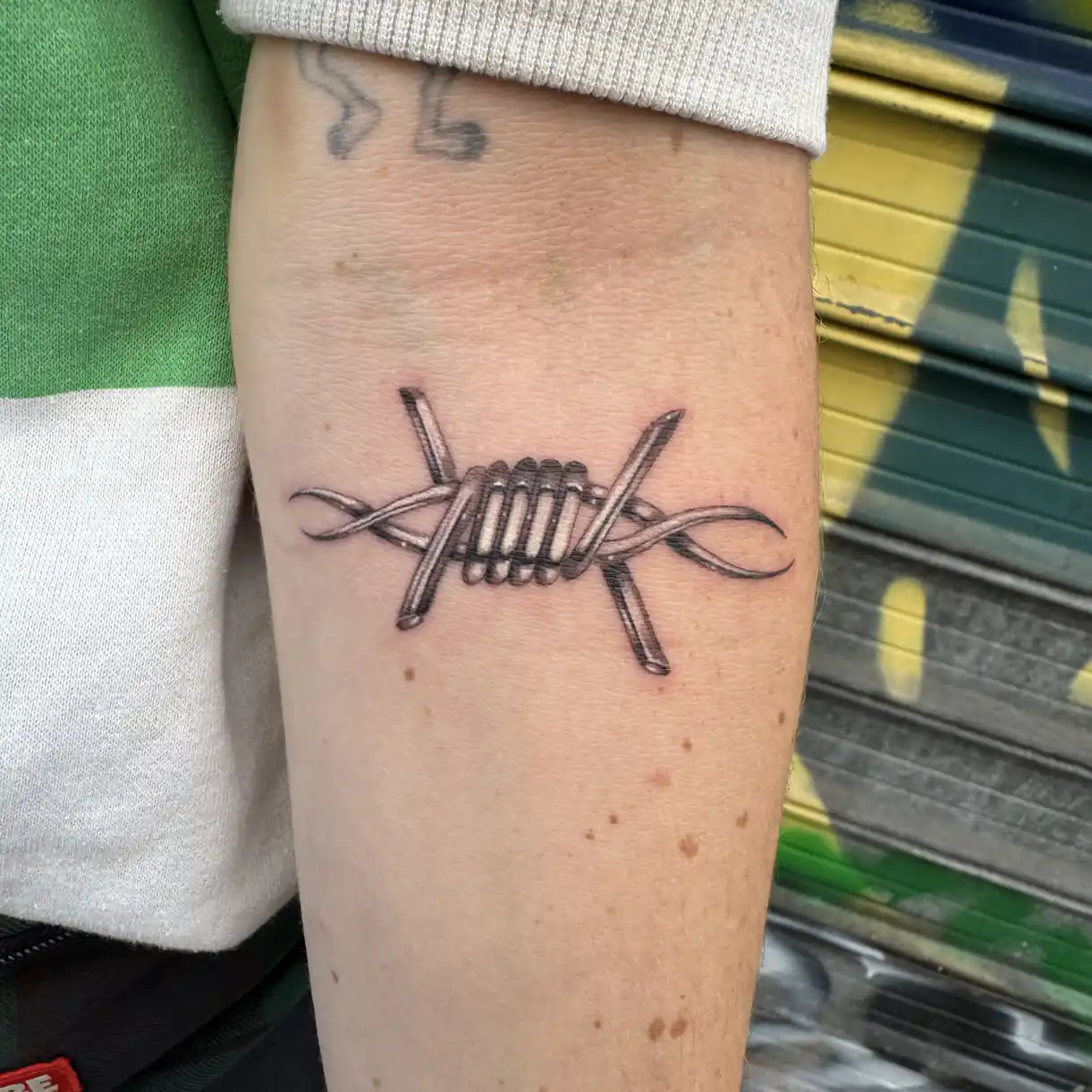Tatouage bold line d'un barbelé sur l'avant-bras — Poutz, Art du Noir Nice