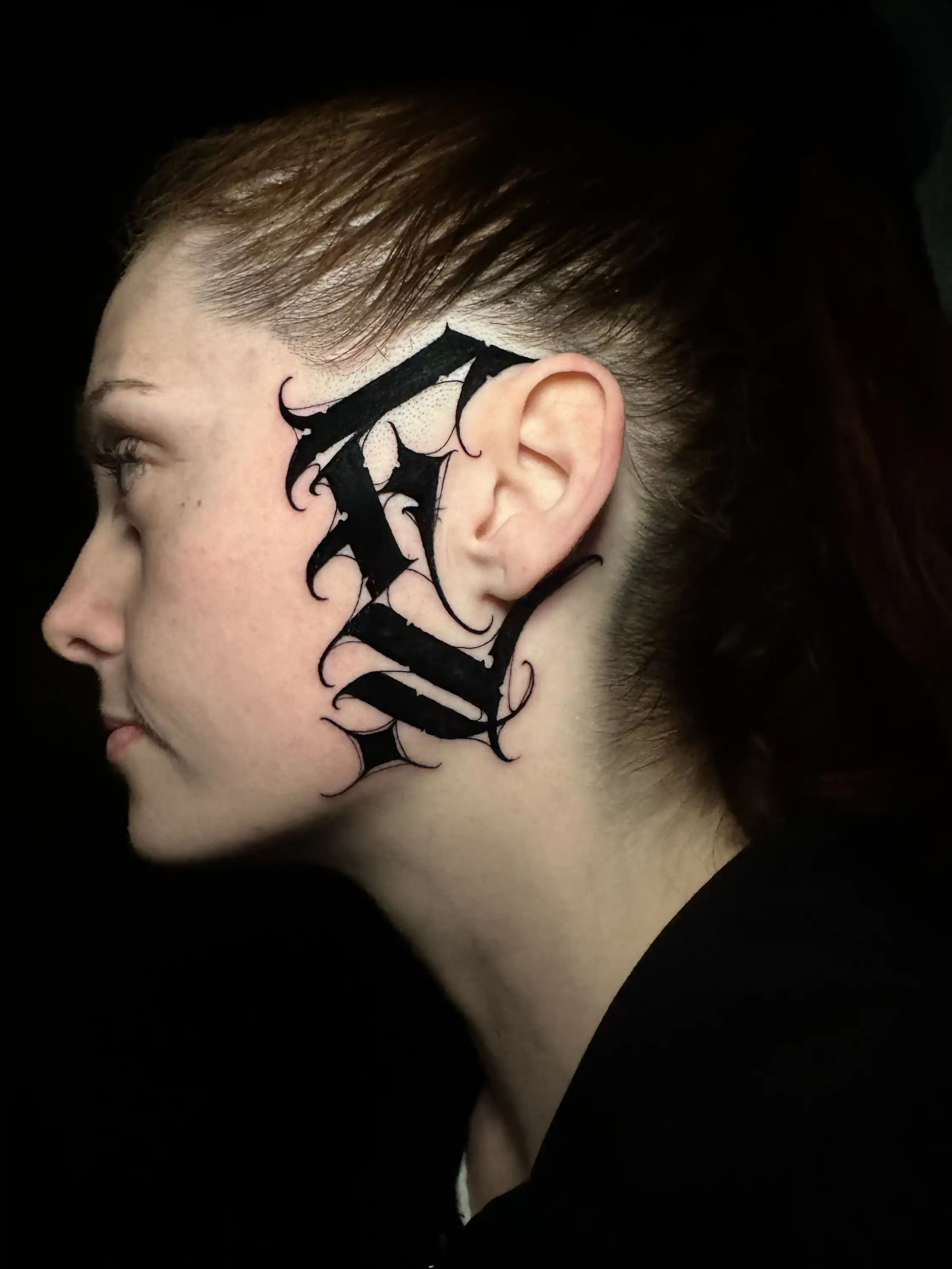 Initiale blackletter tatouée sur la tempe — William Hamer, Art du Noir Nice